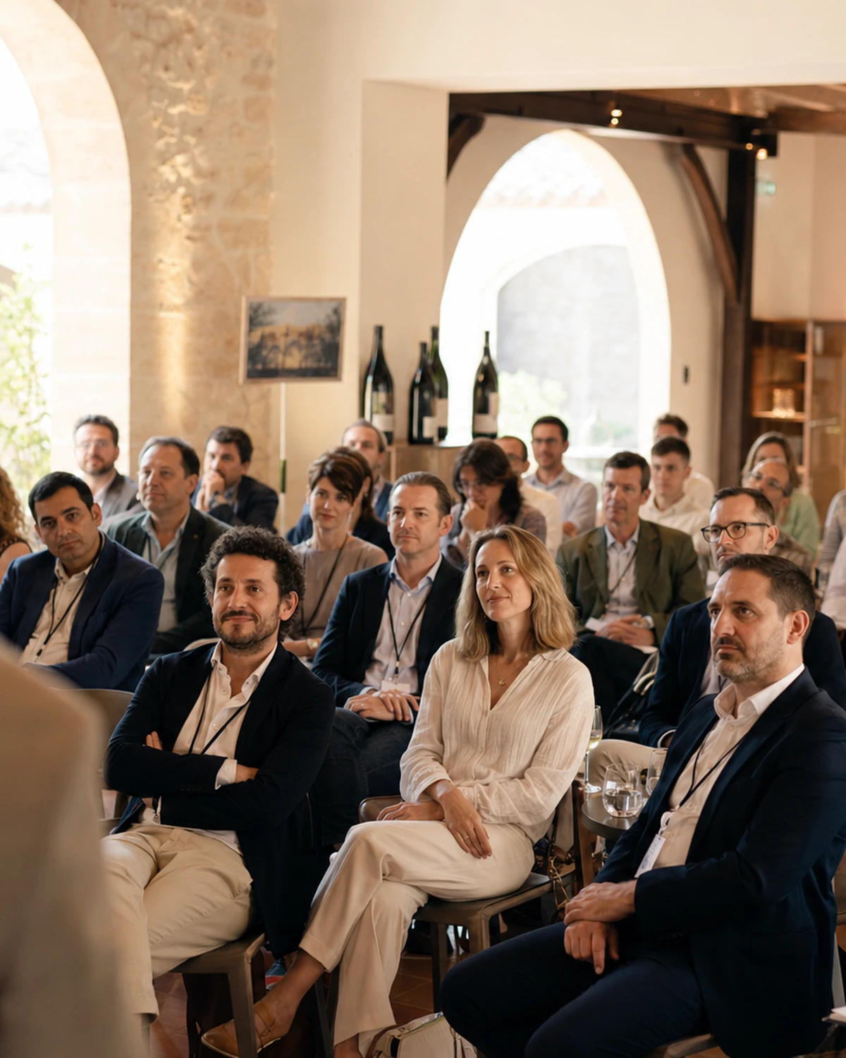 Illustrative scene of a professional gathering in a stone estate hall, with an attentive audience.